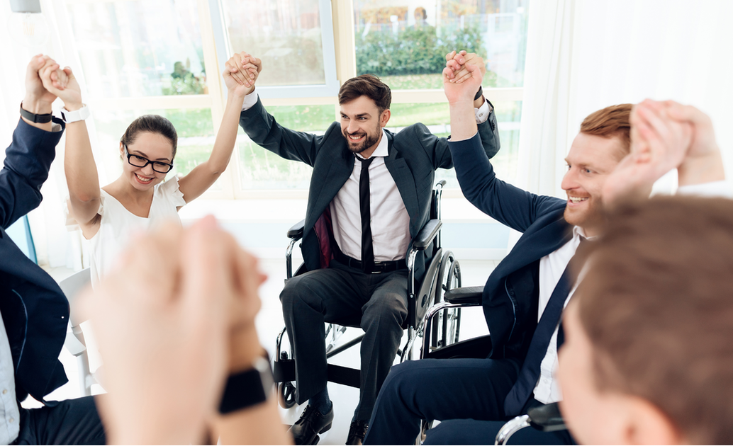 man in wheelchair and coworkers join hands